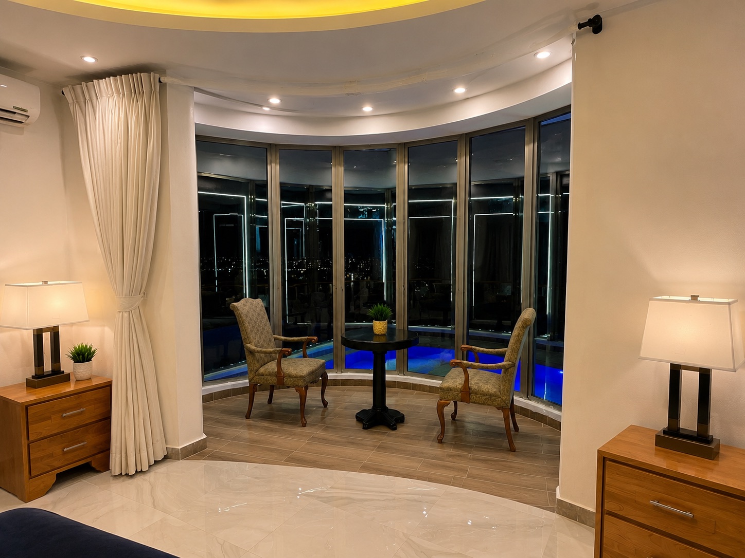 Suite sitting area overlooking the illuminated pool at night